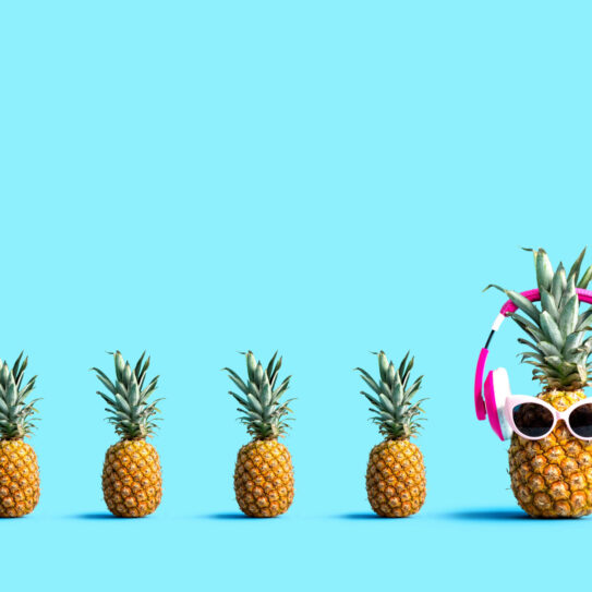 One out unique pineapple wearing headphones on a solid color background