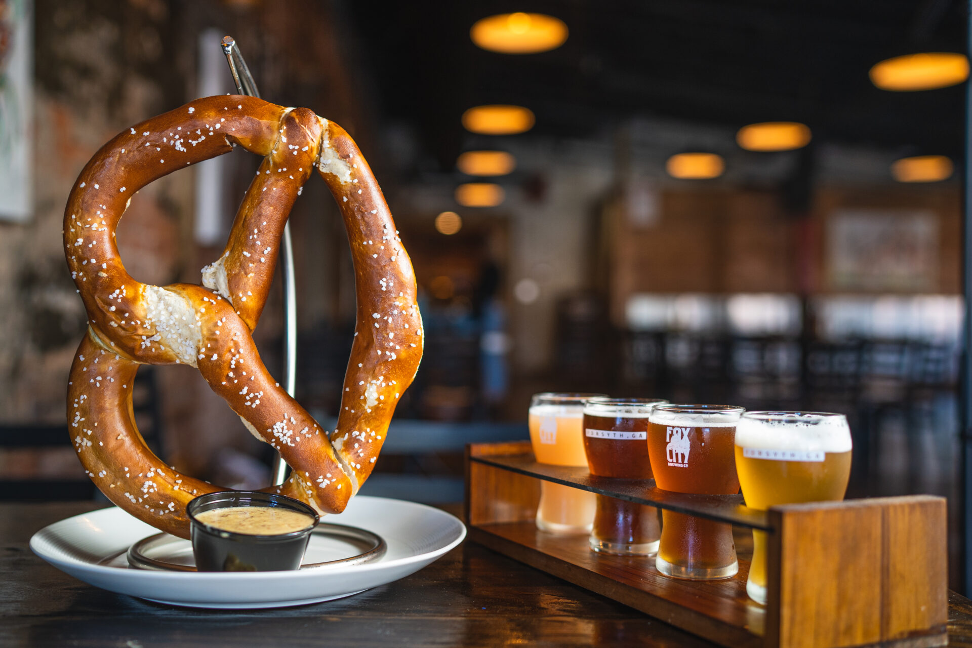 Product photography of a large soft pretzel and a flight of beer from Fox City Brewing in Forsyth, GA.